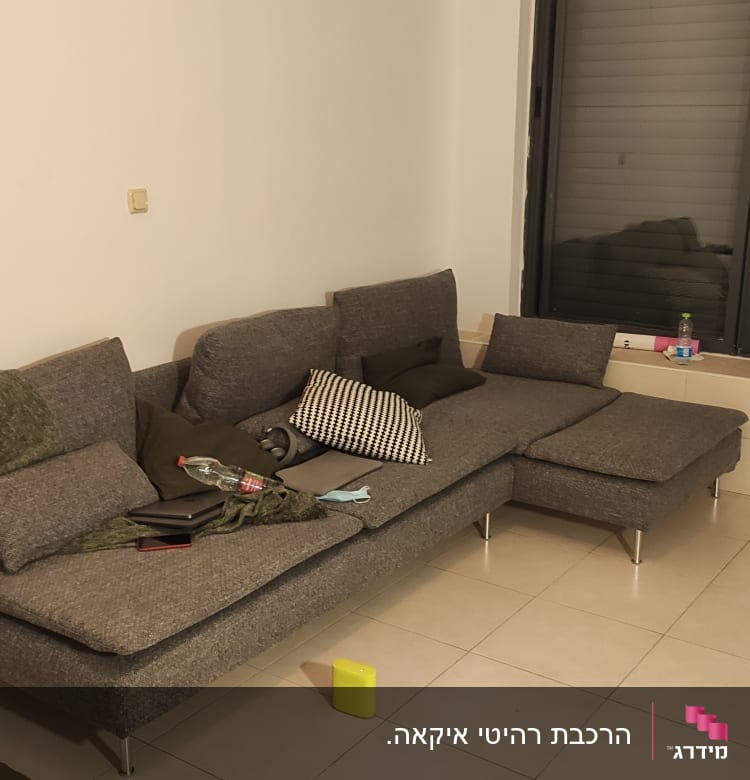 ספה אפורה עם כריות, שולחן קטן עם חפצים